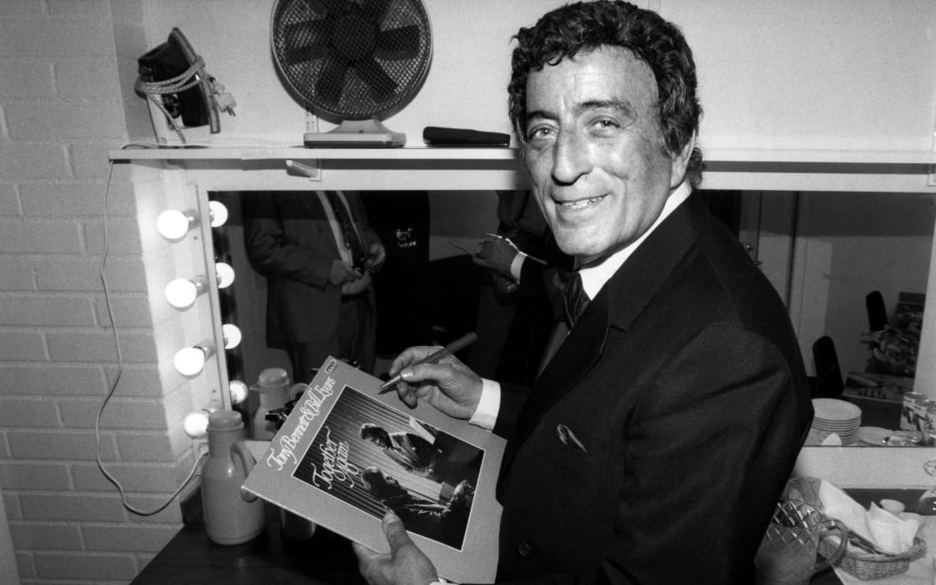 US singer Tony Bennett signs an autograph to a record in his loge on march 6, 1988 after the concert at the Stockholm "Börsen". (Photo by Bernt CLAESSON / PRESSENS BILD / AFP)