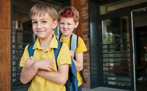 Cheeky children in uniform ready for school.