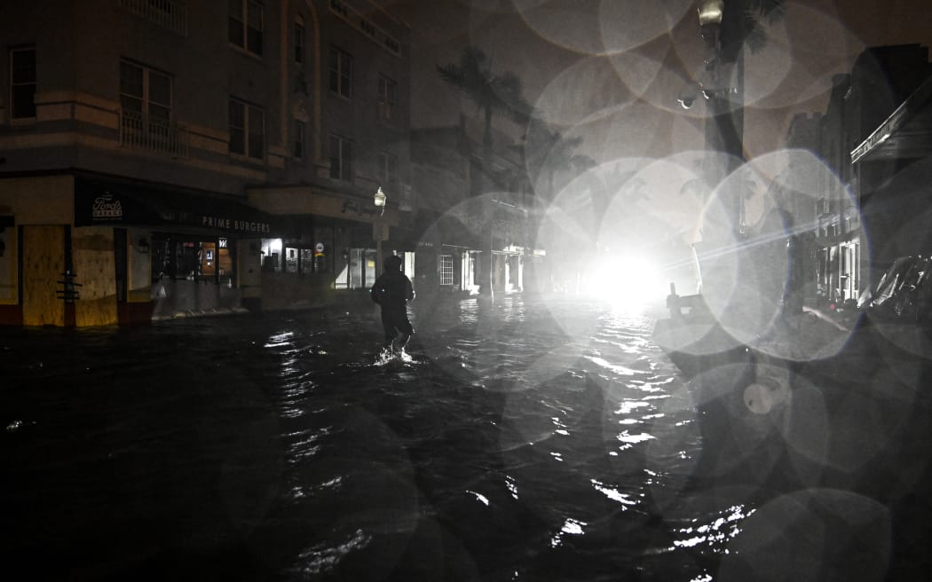 A man walks through water-flooded streets after Hurricane Milton made landfall in Fort Myers, Florida, on October 9, 2024. - Milton made landfall in Florida October 9, 2024 as an "extremely dangerous" Category 3 hurricane, packing life-threatening storm surge, extreme winds and flash flooding, the National Hurricane Center (NHC) said. "Data indicate the eye of Hurricane Milton has made landfall near Siesta Key in Sarasota County along the west coast of Florida," the NHC said in an 8:30 pm (0030 GMT Thursday) bulletin. (Photo by CHANDAN KHANNA / AFP)
