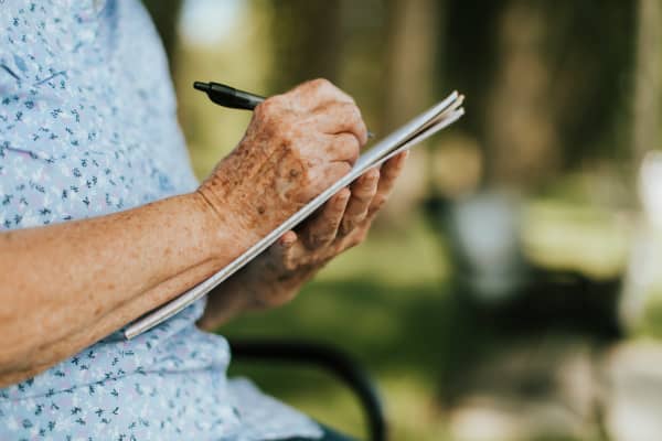 Older person writing into notepad.