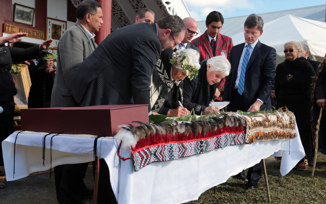 060814. Photo Diego Opatowski / RNZ. Te Tai Hauauru MP Tariana Turia (right) signs as Treaty Negotiations Minister Chris Finlayson looks on (far right).
