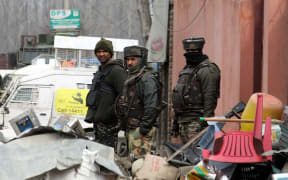Indian paramilitary soldiers stand guard near the encounter site where nine people were killed in fierce gun-battle between militants.