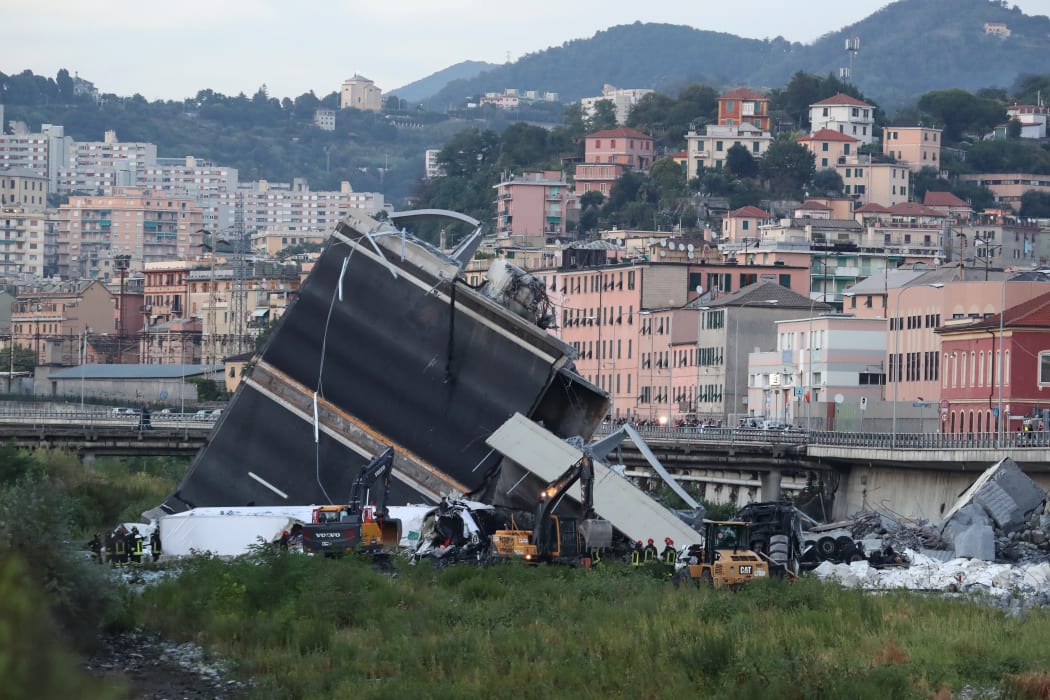 Rescuers inspect the rubble and wreckages by the Morandi motorway bridge after a section collapsed in Genoa.