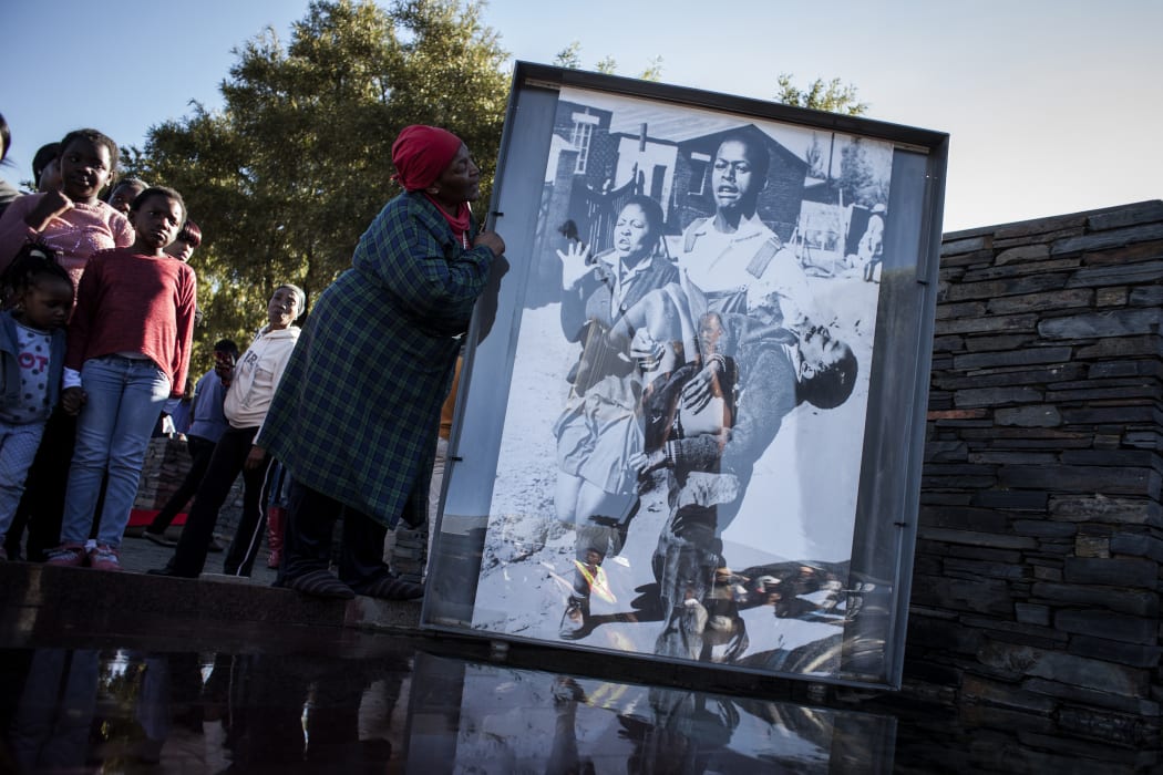 Ms Nontsikelelo Makhubu is seen next to the iconic photograph by Sam Nzima showing Hector Pieterson carried away during the start of the Soweto Uprising in 1976.