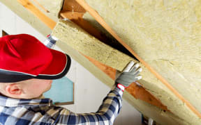 Man installing thermal roof insulation layer using mineral wool panels.