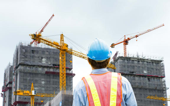 construction worker checking location site with crane on the background