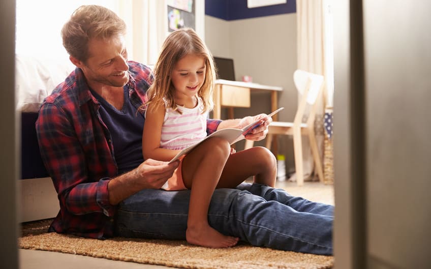 A photo of a father and young daughter reading together