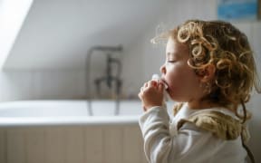 A little kid using a tissue.