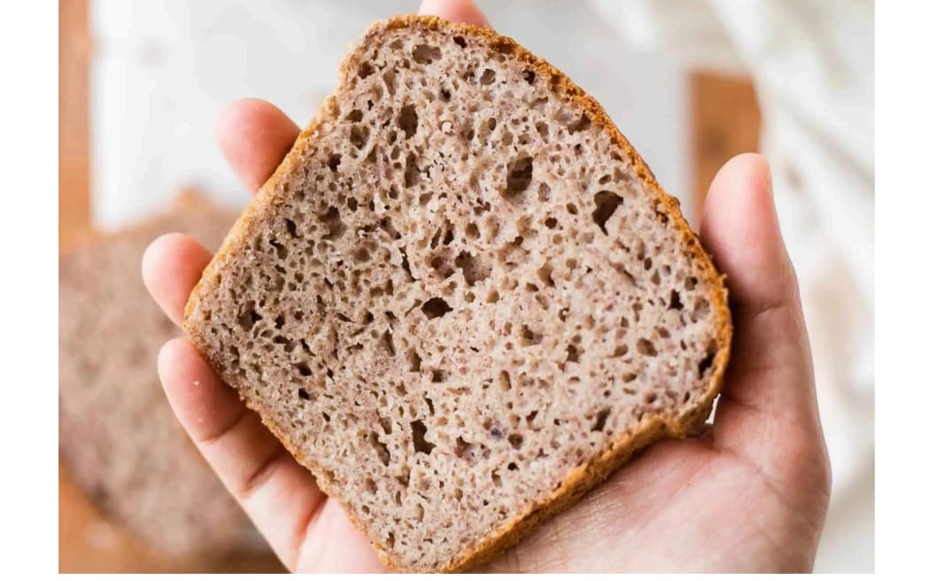 a hand holds up a slice of brown bread