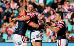 James Tedesco celebrates after scoring with Jared Waerea-Hargreaves and Cooper Cronk.