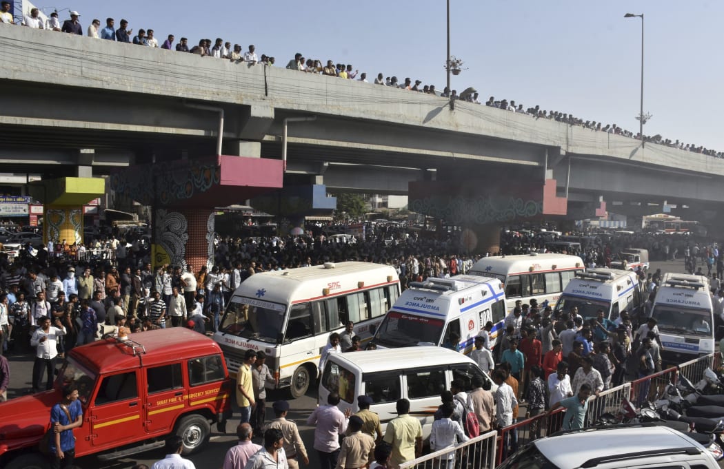 A crowd gathers to watch a building on fire in Surat, in the western Indian state of Gujarat, Friday, May 24, 2019.