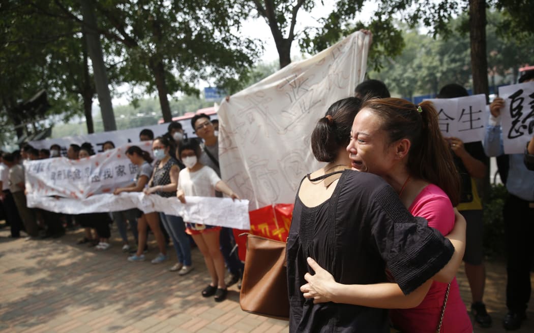 Two women hug one another as they join other residents whose homes were destroyed in the Tianjin explosion.