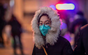 A woman wearing a protective mask walks on the street outside Beijing railway station on January 22, 2020.