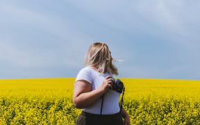 blonde woman with camera in field