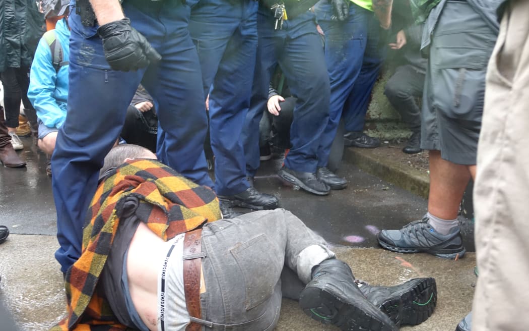A protester on the ground, refusing to move as police try to clear a path for delegates into the conference.