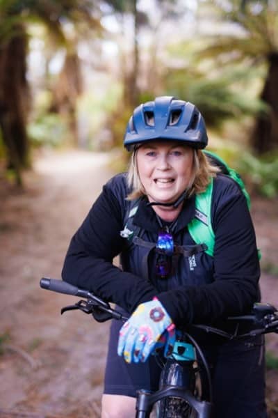 Kath Cross in her mountain biking gear at a forest trail.