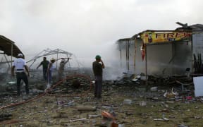 Firefighters and volunteers work amid the smouldering debris left by a blast in a fireworks market near Mexico City.
