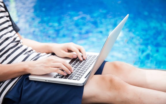 A man with a laptop checks his work emails by the pool (file).