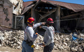 Two firefighters survey a collapsed building after an earthquake hit the island in Guanica, Puerto Rico after a strong earthquake struck early on 7 January, followed by major aftershocks.