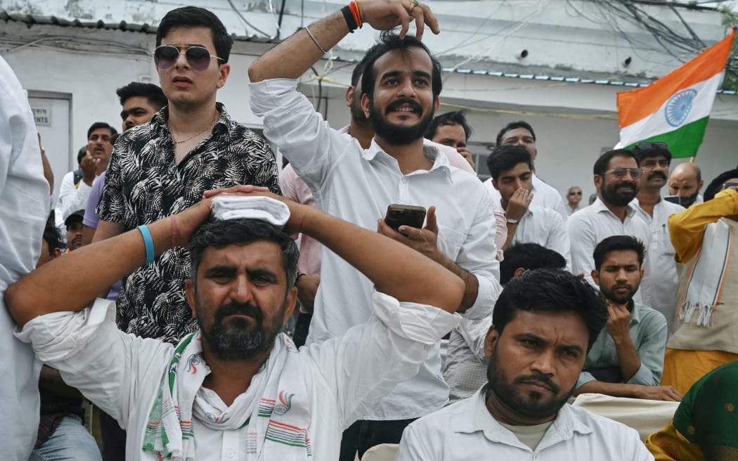 Supporters of Indian National Congress (INC) party react as they watch live election results on a television after counting of votes began for country's general election, at the INC headquarters in New Delhi on June 4, 2024. Vote counting began in India's election on June 4, with Prime Minister Narendra Modi all but assured a triumph for his Hindu nationalist drive that has thrown the opposition into disarray and deepened concerns for minority rights. (Photo by ARUN SANKAR / AFP)