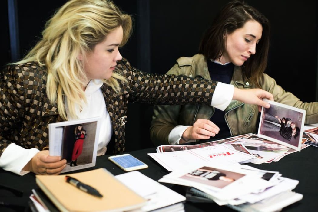 Jessica Grubisa and Madeleine Harman look through model headshots at NZFW model castings.