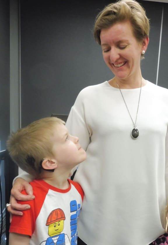 Seven-year-old Charles, pictured with his mum Belinda, has two cochlear implants which have restored his ability to hear to the point that he can play music and learn Chinese.