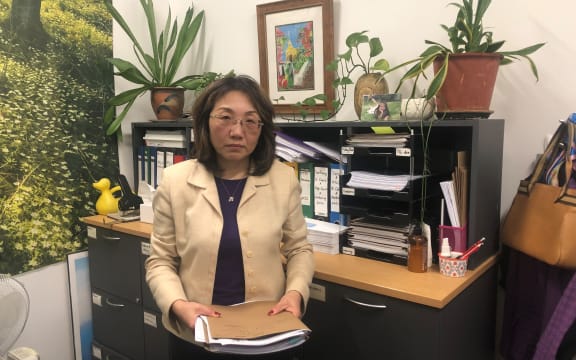 A portrait of employment advocate May Moncur in her office. She is holding casefiles.