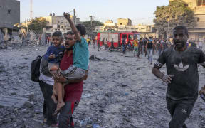 A wounded Palestinian man carries children following a strike in Rafah on the southern Gaza Strip on November 6, 2023, amid the ongoing battles between Isreal and the militant group Hamas. (Photo by Mohammed ABED / AFP)