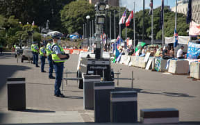 Anti-vaccine, anti-mandate protest in Wellington on Parliament grounds on 16 February 2022. Police standing on forecourt.