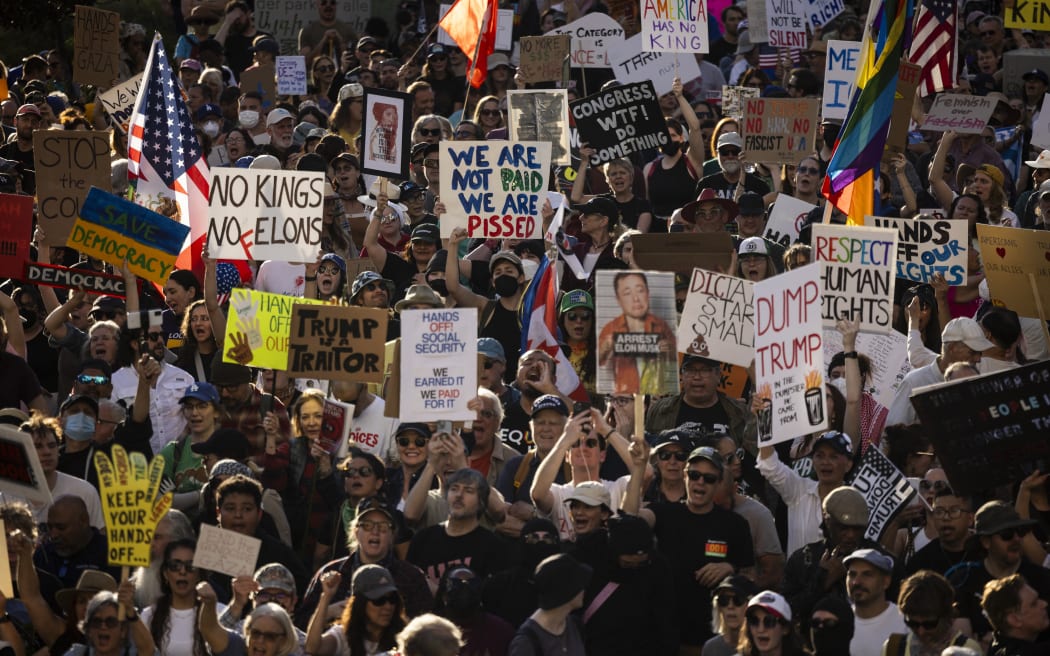 Protesters hold up signs during the nationwide "Hands Off!" protest against US President Donald Trump and his advisor, Tesla CEO Elon Musk, in downtown Los Angeles on April 5, 2025. Protesters flooded the streets of several major US cities on Saturday to oppose the divisive policies of President Donald Trump, in the largest demonstrations since his return to the White House. Opponents of the Republican president's policies -- from government staffing cuts to trade tariffs and eroding civil liberties -- rallied in Washington, New York, Houston, Los Angeles and Florida, among other locations. (Photo by ETIENNE LAURENT / AFP)