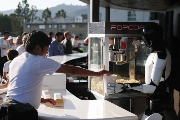 A Tesla Optimus robot serves popcorn on the outdoor deck during the opening of the Tesla Diner and Drive-In restaurant and Supercharger on Santa Monica Blvd in the Hollywood neighborhood Los Angeles, California on July 21, 2025. Elon Musk's electric vehicle company Tesla has opened a diner on Santa Monica Boulevard in Los Angeles.