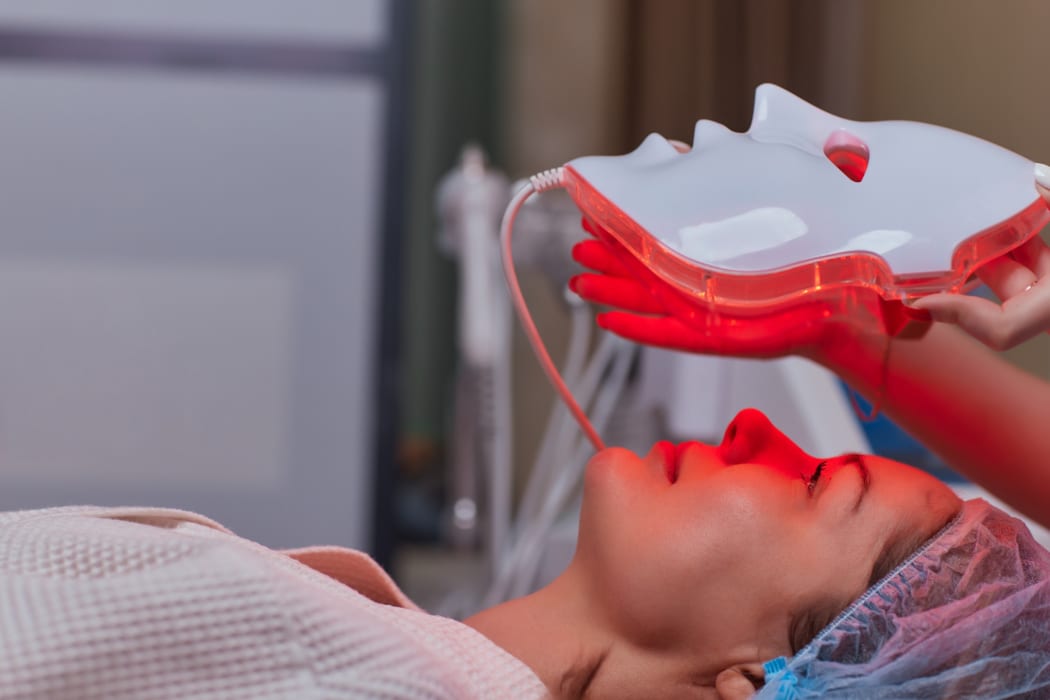 Woman receiving red light therapy face mask treatment