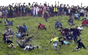 Participants take part in the annual cheese rolling at Cooper's Hill in Brockworth, England, Monday, May 27, 2024. The traditional event attracts people from around the globe who come to chase a 7lb Double Gloucester cheese down the steep Coopers Hill. (Jacob King/PA via AP)