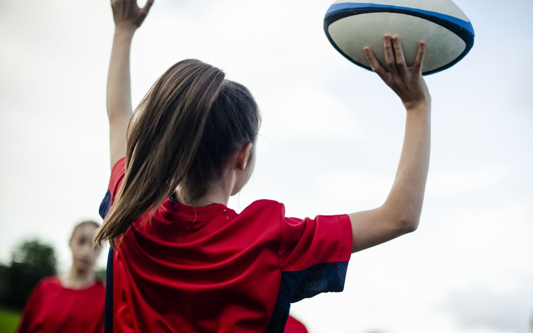 Female rugby player jumping with a ball