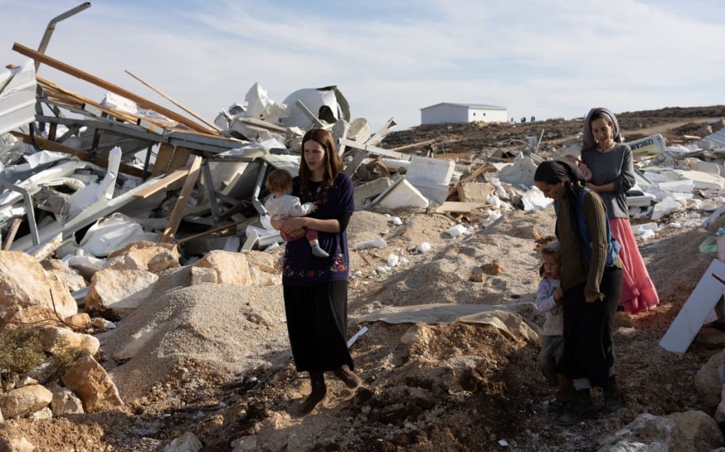 Israeli settlers walks at an illegal outpost built near the Jewish settlement of Metzad east of the Palestinian city of Sa’ir in the occupied West Bank after being demolished by Israeli security forces, on 17 November 2025.