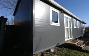 A tiny house on wheels in the backyard of a Renwick house,