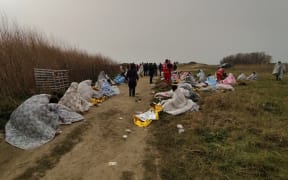 This photo obtained from Italian news agency Ansa, taken on February 26, 2023 shows rescued migrants wrapped in a blanket in Steccato di Cutro, south of Crotone, after their boat sank off Italy's southern Calabria region. - More than 30 migrants, including a tiny baby, died after their overloaded boat sank early on February 26, 2023 in stormy seas off Italy's southern Calabria region, Italian media and rescue services reported. (Photo by STRINGER / ANSA / AFP) / Italy OUT