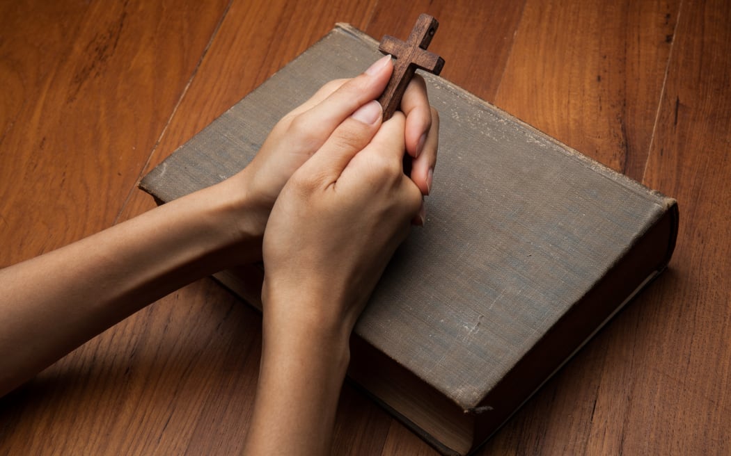 Hands folded in prayer over Holy Bible