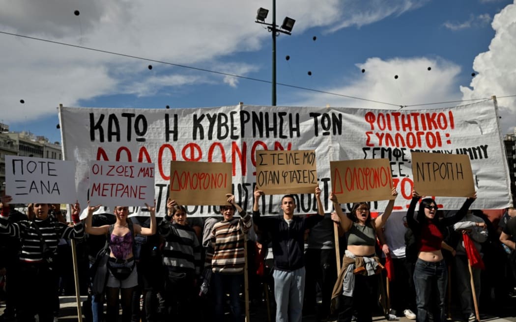 Youths hold placards, some reading "Murderers" in front of the Greek parliament during a demonstration in Athens on March 5, 2023, following a deadly train accident late on February 28. - Violent clashes broke out between police and protesters outside the Greek parliament in Athens on March 5 as thousands attended a rally following the nation's worst rail disaster that killed 57, AFP reporters saw. (Photo by Louisa GOULIAMAKI / AFP)