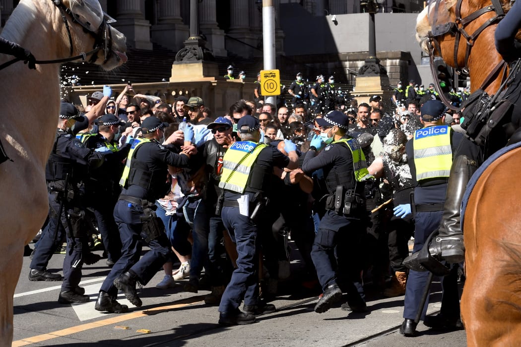 Police pepper spray protesters during an anti-lockdown rally in Melbourne today.