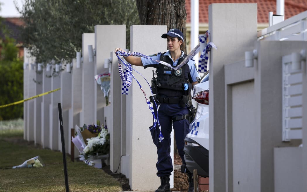 A police officer lifts tape to let a car into the Christ the Good Shepherd Church in Sydney's western suburb of Wakeley on April 16, 2024. Australian police on April 16 said a brutal knife attack during a live-streamed church service was a religiously motivated "terrorist" act, as they urged calm from the angered local community. (Photo by DAVID GRAY / AFP)