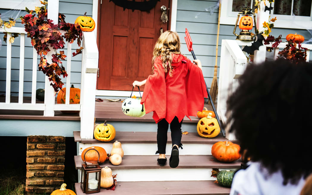 Child in red costume on door step, trick or treating for halloween.