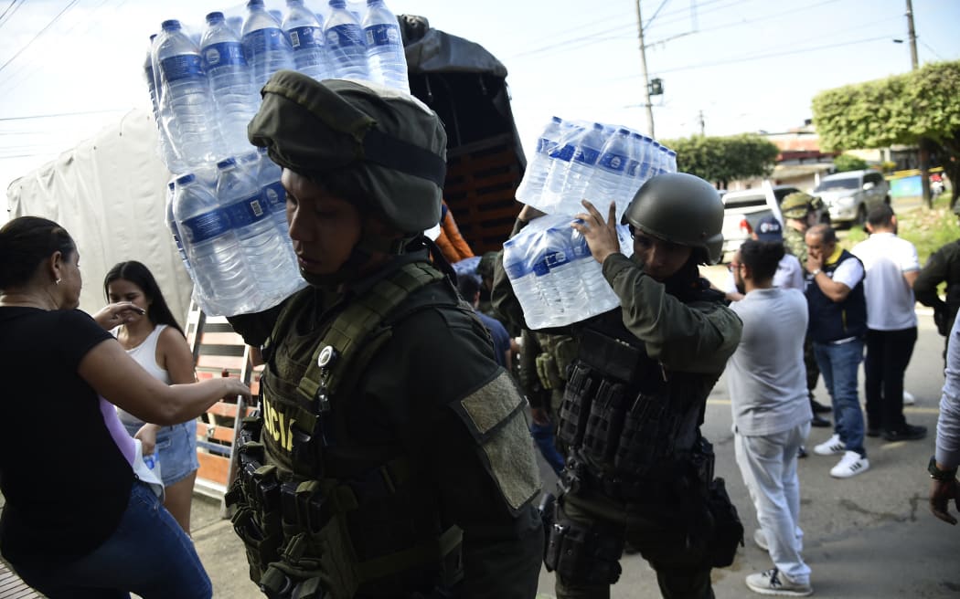 Police officers unload humanitarian aid for displaced people from recent clashes between armed groups in Tibu, Norte de Santader Deparment, Colombia, on January 19, 2025. A fresh outbreak of guerrilla violence amid a faltering peace process in conflict-riddled Colombia has left more than 80 people dead in just over three days, officials reported Sunday. The National Liberation Army (ELN) armed group launched an assault in the northeastern Catatumbo region last Thursday on a rival formation comprised of ex-members of the now-defunct FARC guerrilla force who kept fighting after it disarmed in 2017. (Photo by Schneyder Mendoza / AFP)