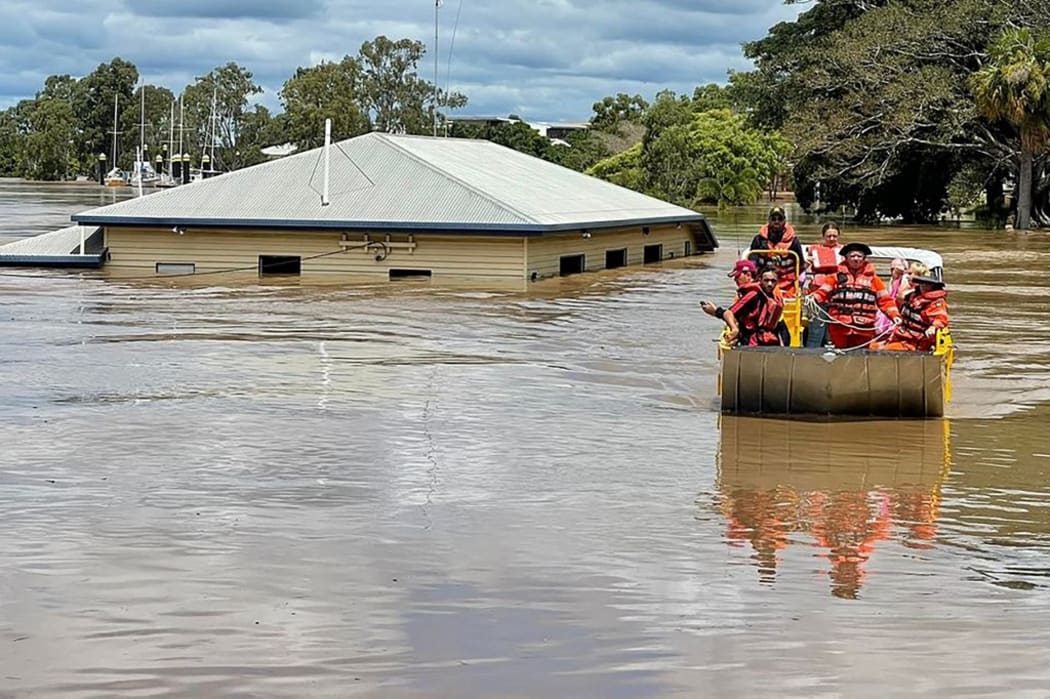 This handout photo taken on February 28, 2022 and received on March 1 from the Queensland Fire and Emergency Services shows rescuers on a boat evacuating people along a flood street around Maryborough in Queensland.