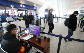 Staff members take passengers' body temperature at Tianhe International Airport in Wuhan, capital of central China's Hubei Province, Jan. 21, 2020.
