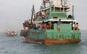 Fishermen help rescue a boat of Rohingya migrants off the coast of Indonesia's East Aceh on 20 May 2015.