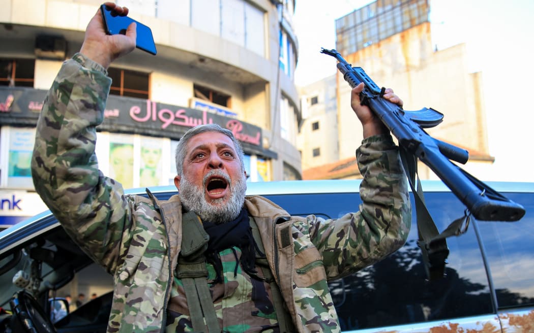 A Syrian rebel fighter who returned to the central city of Homs on December 8, 2024, after being in exile for 12 years celebrates after rebel forces entered Syria's third city overnight.