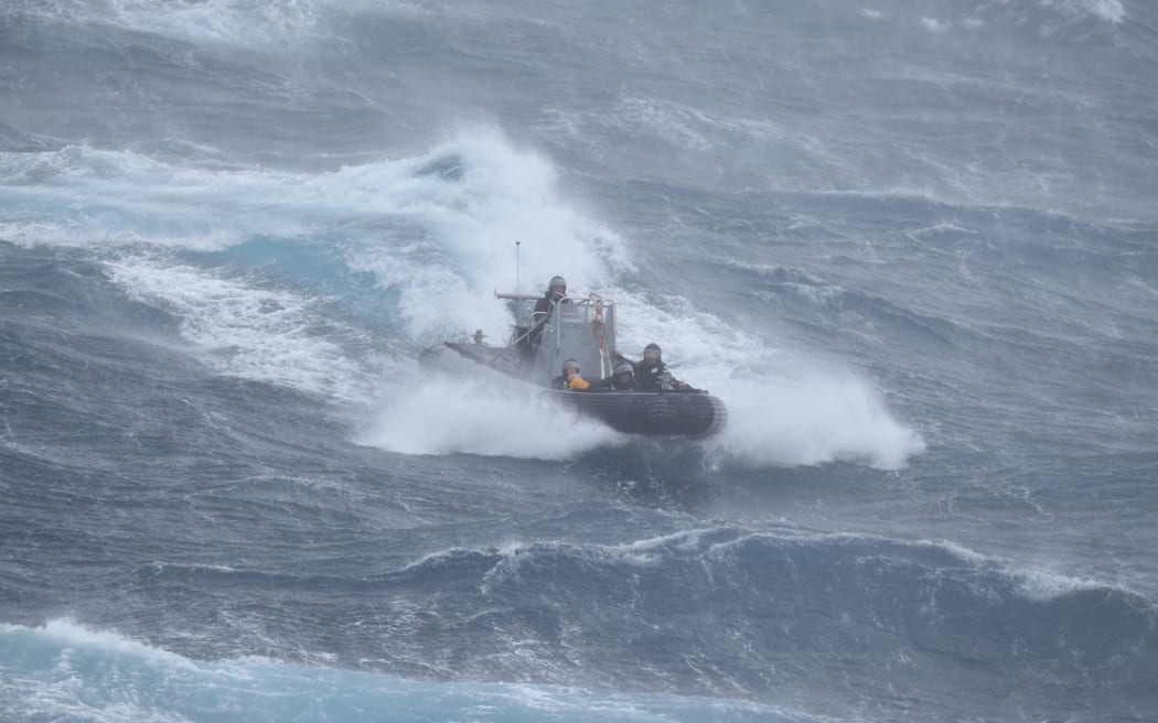 Members of the navy take a man to safety in an inflatable hull vessel after his catamaran drifted out to sea in strong winds.