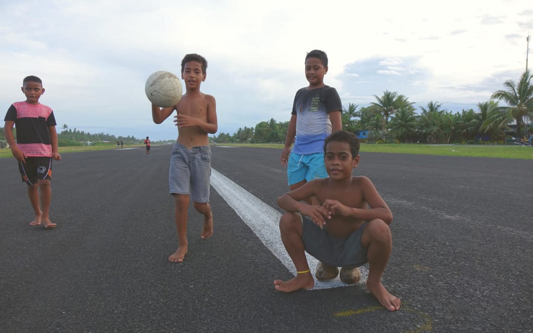 Boys play on the runway, whih takes up most of the space on narrow Fogafale, Tuvalu