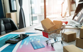 E-commerce. Paper boxes in shopping cart and credit card with smartphone on sales data economic growth graph, online shopping and payments, banking, buying and selling services online on network.